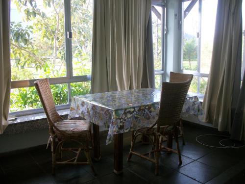 a table and chairs with a table and windows at Apartamento Porto Bracuy Apartment in Angra dos Reis