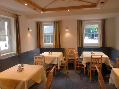 a restaurant with white tables and chairs and windows at Pension Gondelstube in Schladming