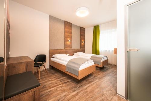 a hotel room with two beds and a desk at Das schlaf&GUT - Self Check-In in Leibnitz