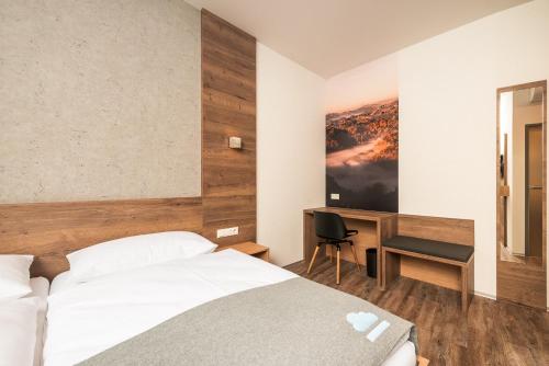 a hotel room with a bed and a desk at Das schlaf&GUT - Self Check-In in Leibnitz
