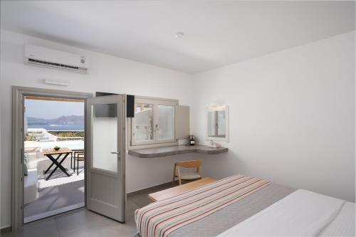 a white bedroom with a bed and a balcony at Hotel Goulielmos in Akrotiri