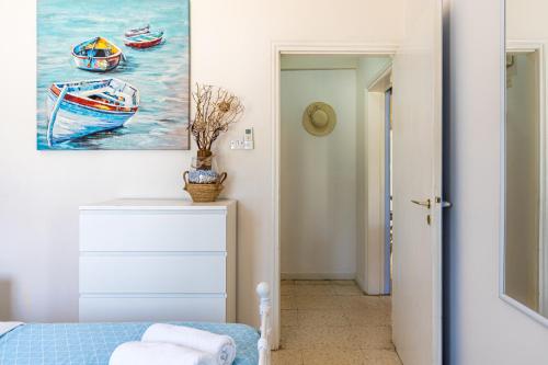 a bedroom with a painting of boats on the wall at Sea Breeze 1-BR Apt in Pyla in Pyla