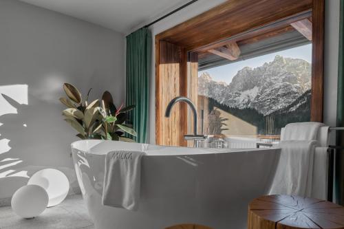 a bath tub in a bathroom with a mountain view at Milka Boutique Hotel in Kranjska Gora