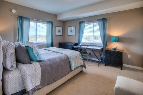 Schlafzimmer mit einem Bett, einem Schreibtisch und Fenstern in der Unterkunft Vista Del Mar Condo - Oyhut Bay Seaside Village in Ocean Shores