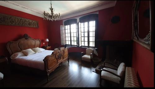 1 dormitorio con paredes rojas, 1 cama y 1 silla en Hotel Rural las Cinco Ranas en Brazatortas