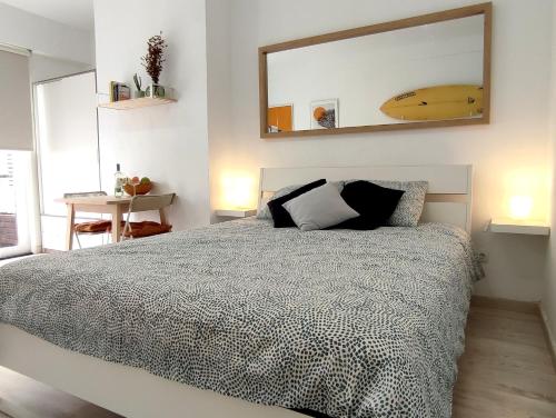 a bedroom with a bed with a mirror and a surfboard on the wall at Las Canteras Suite in Las Palmas de Gran Canaria