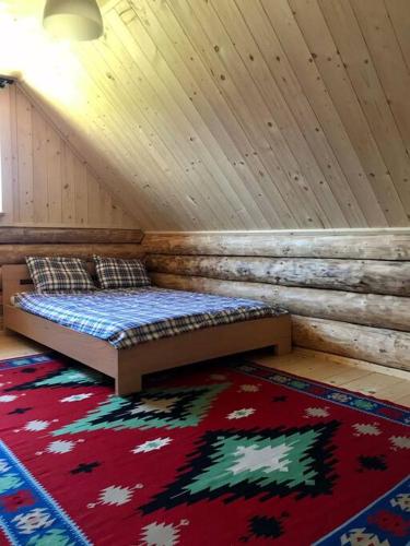 a room with a bed in a attic with a rug at Chatka_Kasina in Kasina Wielka