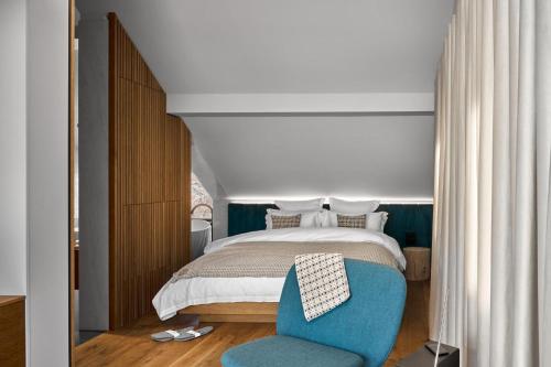 a bedroom with a bed and a blue chair at Milka Boutique Hotel in Kranjska Gora