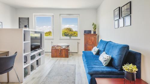 uma sala de estar com um sofá azul e uma televisão em Apartamenty Sun & Snow Katamarany Zatoka em Puck