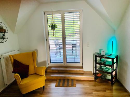 a living room with a yellow chair and a sliding glass door at Zur Rotbuche in Zeltingen-Rachtig
