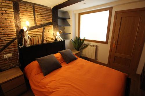 ein orangefarbenes Bett in einem Zimmer mit Ziegelwand in der Unterkunft Monkeys House. in Vitoria-Gasteiz