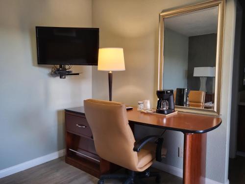 uma secretária num quarto de hotel com uma cadeira e um espelho em Star Inn Barstow em Barstow