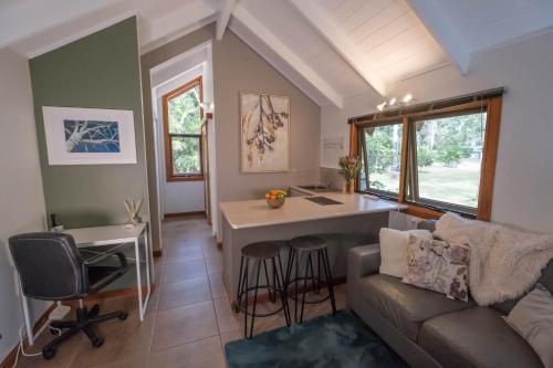 a living room with a couch and a kitchen with a desk at Airlie Beach Eco Cabins - Adults Only in Airlie Beach