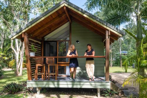two women standing on the porch of a tiny house at Airlie Beach Eco Cabins - Adults Only in Airlie Beach