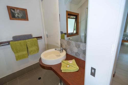 a white bathroom with a sink and a mirror at Airlie Beach Eco Cabins - Adults Only in Airlie Beach