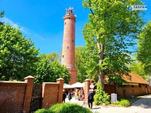 a lighthouse in a park with people walking around it at Apartamenty Na Fali w Gąskach - 365PAM in Gąski