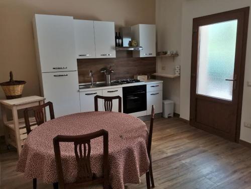 uma cozinha com mesa e cadeiras e uma cozinha com electrodomésticos brancos em Al Centesimo Chilometro - Ristoro del Pellegrino em Montefiascone