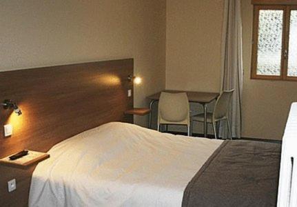 a hotel room with a bed and a table and chairs at La Tour Des Lys in Maubeuge