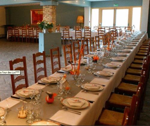 une longue table avec des assiettes et des verres dans l'établissement La Tour Des Lys, à Maubeuge