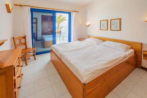 a bedroom with a bed and a table and a window at NUDIST Castillo de Papagayo in Charco del Palo