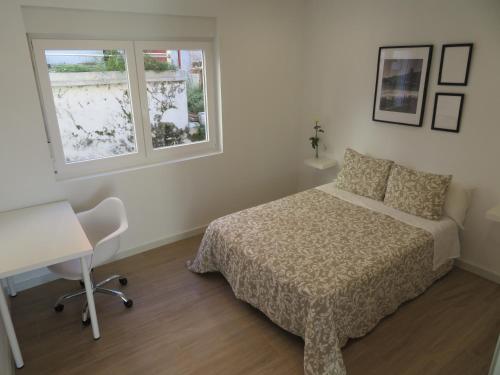 um quarto com uma cama, uma secretária e uma janela em Apartamento Na Beira Do Mar em O Pindo