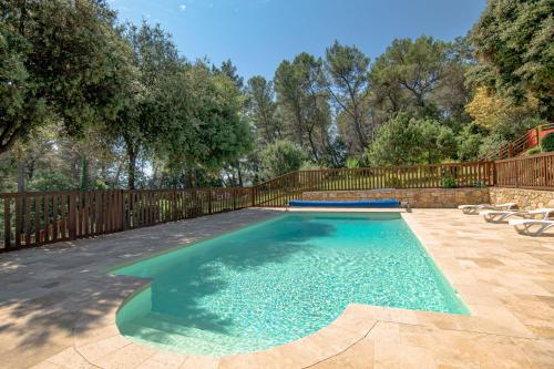 a swimming pool in a backyard with a wooden fence at Le Mas des Bois in Le Muy