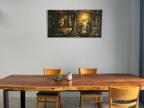 a wooden table with chairs and a painting on the wall at WELKOM INN in Can Tho