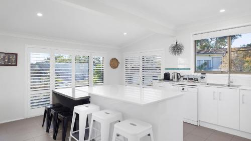 a white kitchen with white counters and stools at Diggers Drive No11 in Lemon Tree Passage