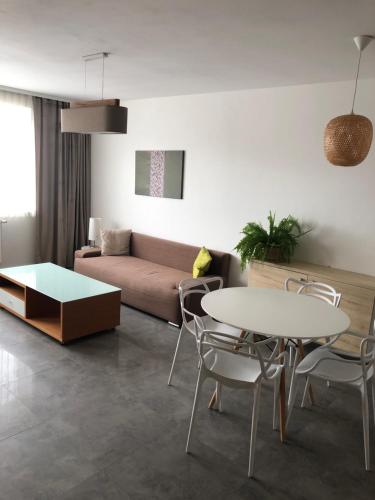 uma sala de estar com um sofá, uma mesa e cadeiras em Apartamenty MAJA Nowy Targ em Nowy Targ
