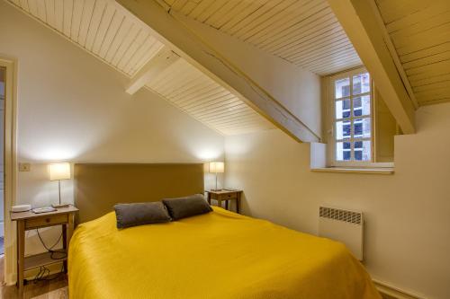 une chambre avec un lit jaune et une fenêtre dans l'établissement Chez Alice appartement en plein centre ville, à Sarlat-la-Canéda