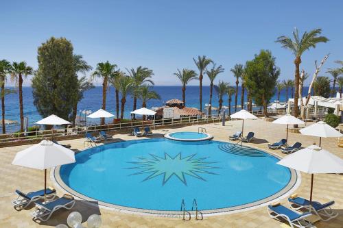 a large swimming pool with chairs and umbrellas at Steigenberger Hotel & Nelson Village, Taba in Taba