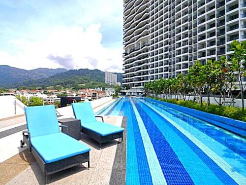 a swimming pool with two chairs and a building at Large Family Seaview Suite 3 Rooms by The Only Bnb in Tanjong Tokong