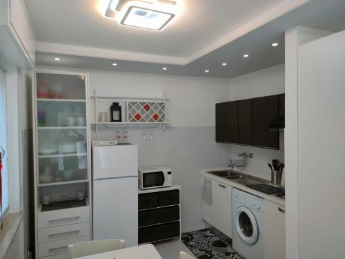 a kitchen with a white refrigerator and a microwave at Appartamento Mirabell, FRONTE SPIAGGIA, VISTA MARE CON PARCHEGGIO in Grado