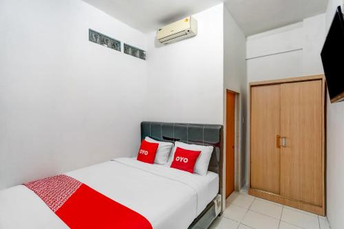 um quarto com uma cama com almofadas vermelhas em OYO 91110 Wilson Homestay em Medan