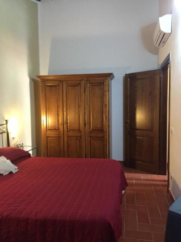 a bedroom with a red bed and wooden cabinets at Corte Tommasi Residence in Orentano
