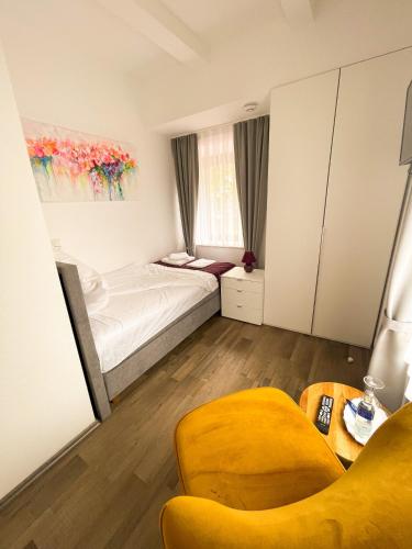 a bedroom with a bed and a yellow chair at Hotel Kronenkurve in Bergkamen