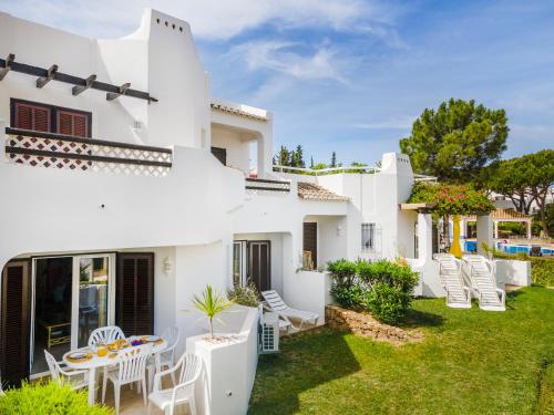 ein weißes Haus mit einem Garten mit Stühlen und einem Tisch in der Unterkunft Albufeira Family Holidays @ Balaia 143 in Albufeira