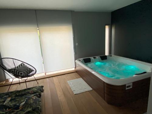 a bath tub in a room with a chair at Villa 96 Golf de la Baule avec piscine et spa in Saint-André-des-Eaux