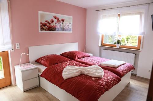 a bedroom with a large bed with red sheets at Ferienwohnung Zur Wolfskehln in Viereth-Trunstadt