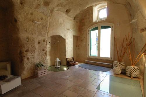 Cette grande chambre dispose d'une fenêtre et d'un mur en pierre. dans l'établissement Il Casale di Maria, à Matera