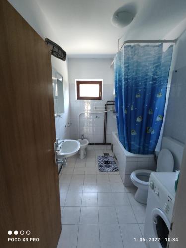 a bathroom with a blue shower curtain and a sink at Bruna's apartment in Vrulje