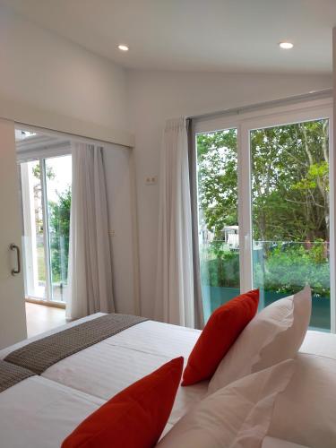 a bedroom with a large bed with red pillows at Píllaras da Lanzada in A Lanzada