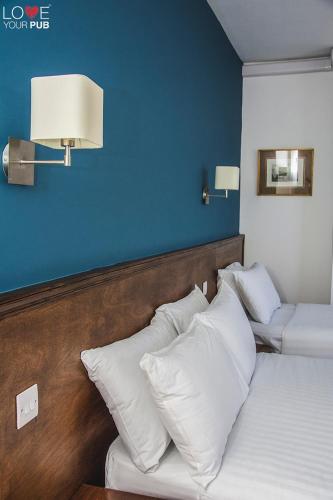 a bedroom with two beds with white pillows and a blue wall at Keppels Head Hotel in Portsmouth
