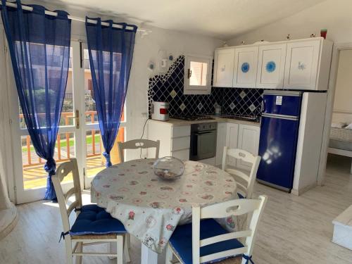 cocina con mesa y sillas y cocina con cortinas azules en Bados affaccio sul mare en Olbia
