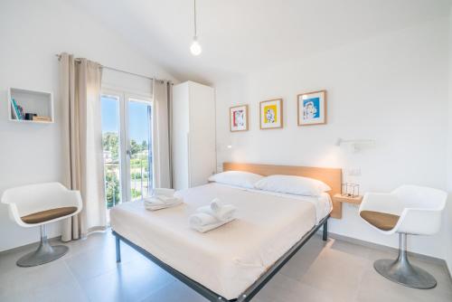 1 dormitorio blanco con 1 cama y 2 sillas en Villa Gio' - 200 mt from the beach - AC, en Torre delle Stelle