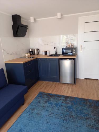a kitchen with blue cabinets and a blue couch at Orzechowa Przystań in Ustka