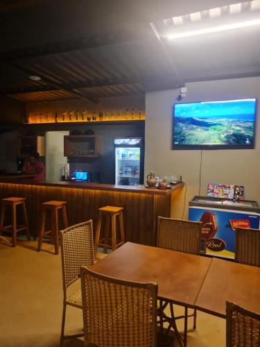 a bar with a table and chairs and a television on the wall at Pousada Terraço Guarapari in Guarapari