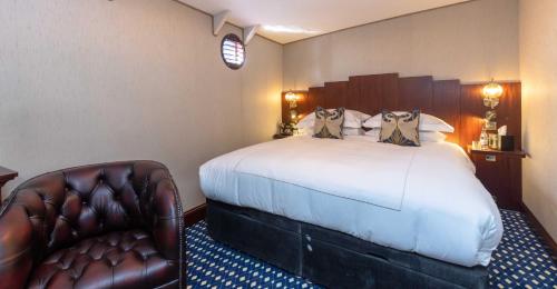 a hotel room with a bed and a leather chair at Ocean Mist Leith in Edinburgh
