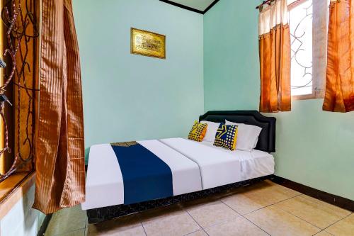 1 dormitorio con 1 cama con paredes y ventanas azules en SPOT ON 91159 Kost Putrana Syariah, en Cilimus 2
