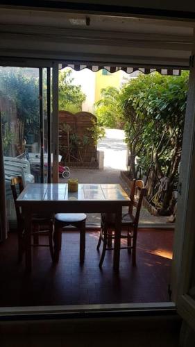 - une table et des chaises sur une terrasse couverte avec une fenêtre dans l'établissement Studio cabine climatisé rez de jardin plage 150m Boucanet, au Grau-du-Roi